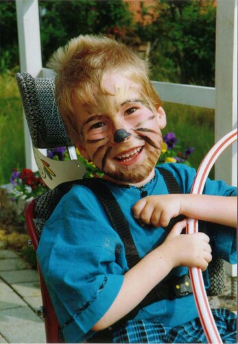 Ein Junge lächelt in die Kamera. Er ist im Gesicht geschminkt wie ein Löwe.